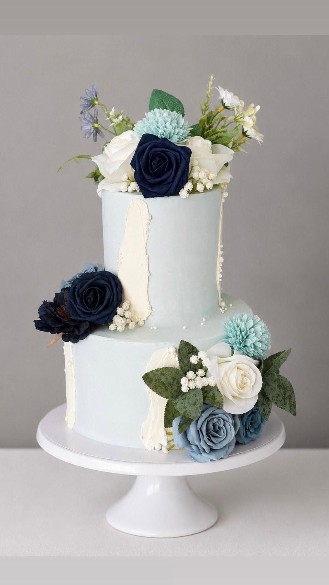 Two tier pale blue wedding cake with fresh flowers