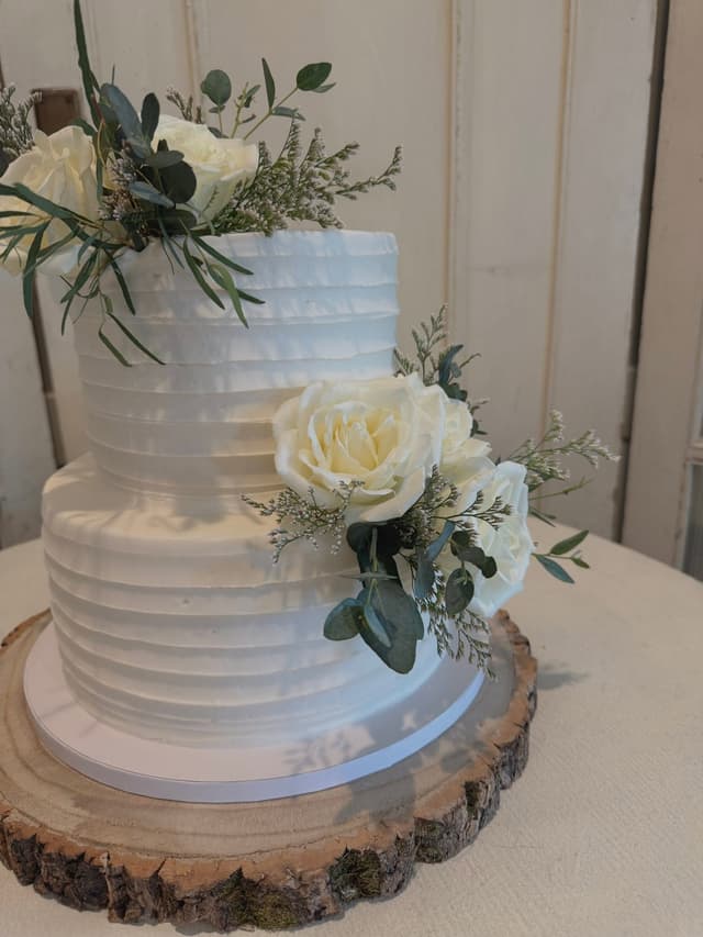 Two tier white ruffled wedding cake with cream roses