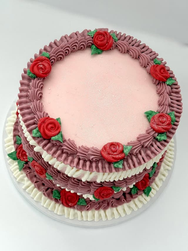 Vintage piped pink cake with red buttercream roses